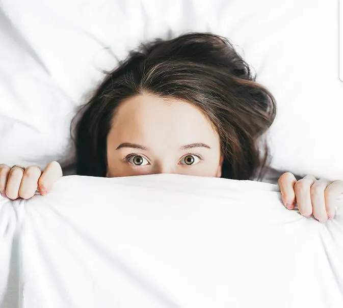 Screen-Shot-2023-05-10-at-9.18.43-AM Person peeking above white blanket in bed.