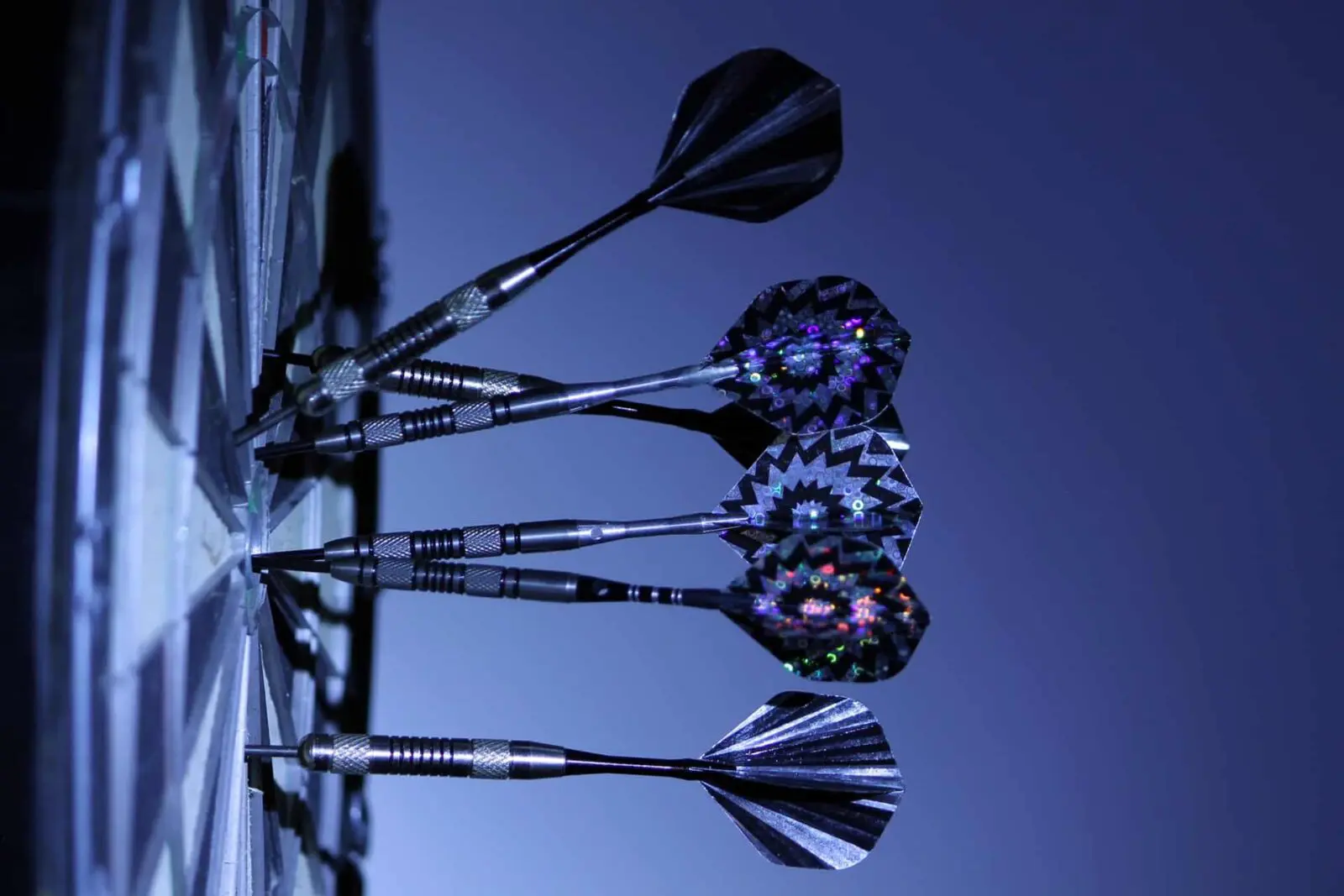 darts-dart-board-bull-s-eye-game-70459 Darts stuck in dartboard, low light.