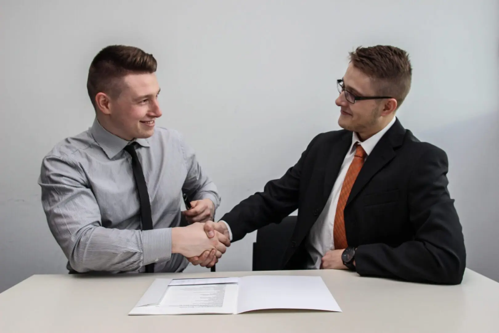 Two men shaking hands over documents.