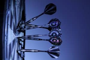 A group of darts on the wall in front of a blue sky.