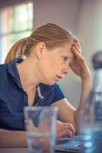 A woman sitting at a table with her head in her hand.