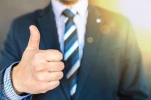 A man in a suit giving the thumbs up.