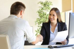 A man and woman shaking hands at an office desk image