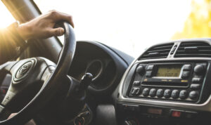 A person is driving in the car and holding on to the steering wheel.