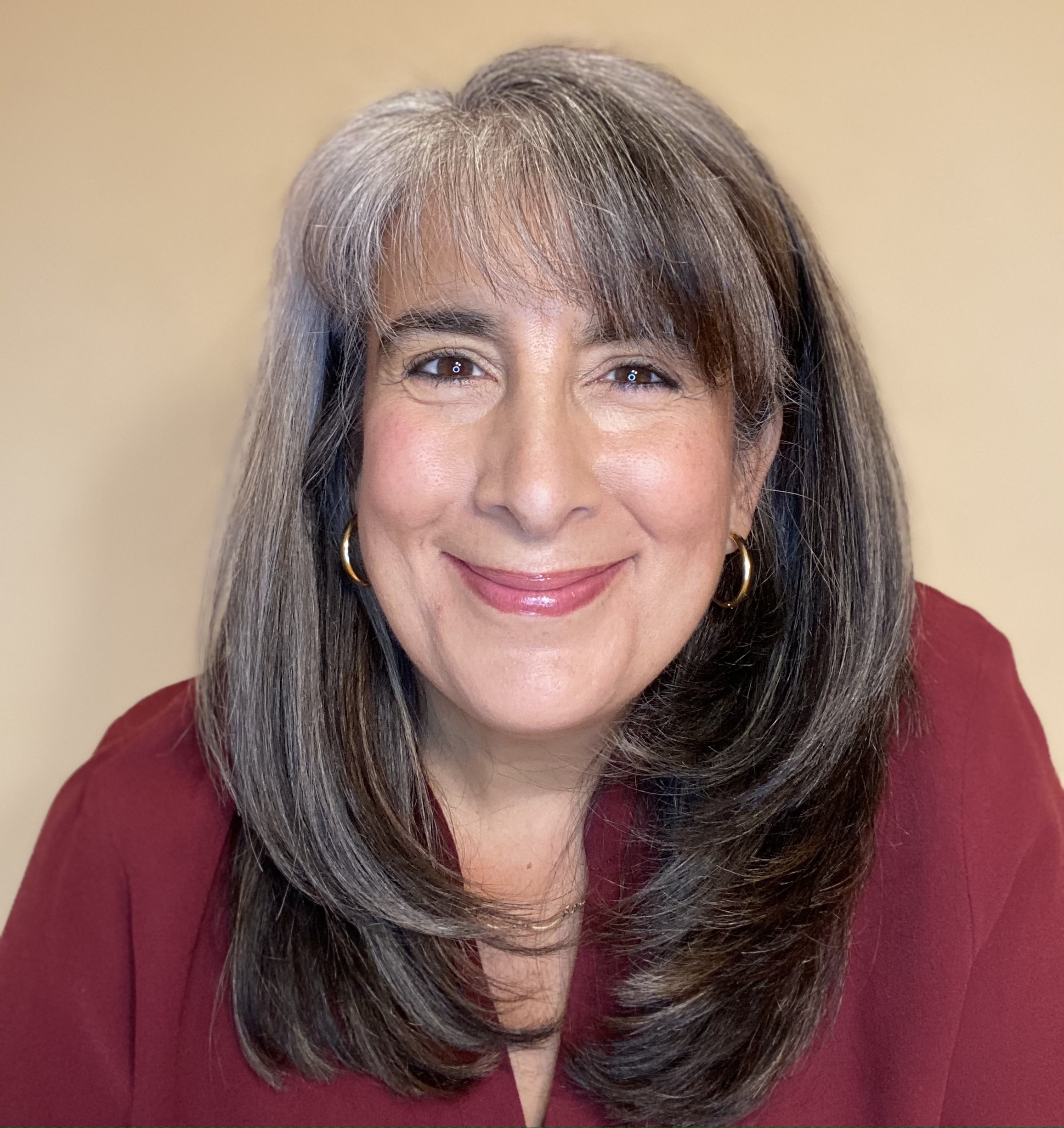 A woman with long grey hair and wearing red.