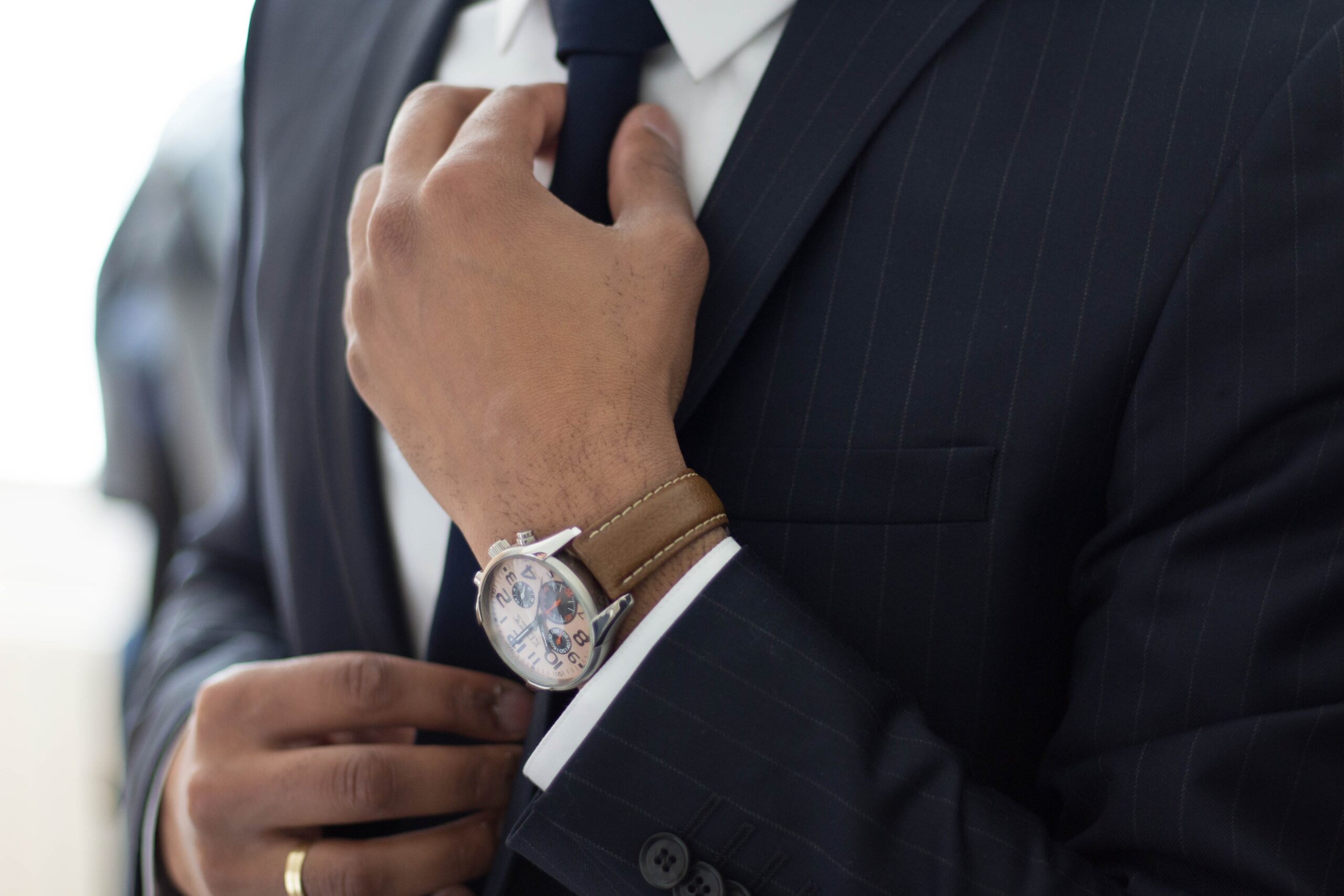 A man in suit and tie adjusting his watch.