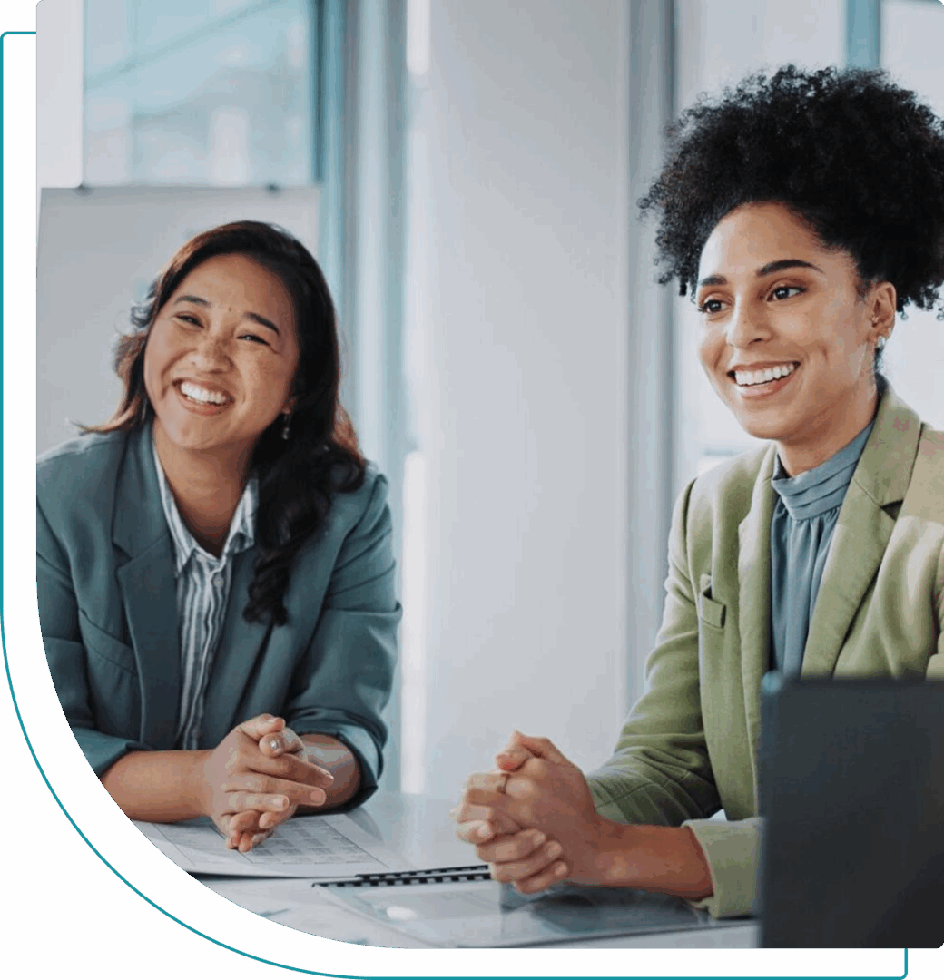 Two women engaged in a friendly office meeting with a laptop.