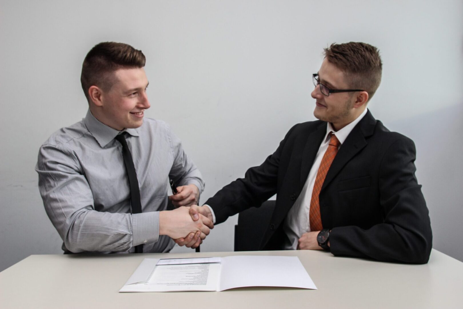 Two men shaking hands over documents.