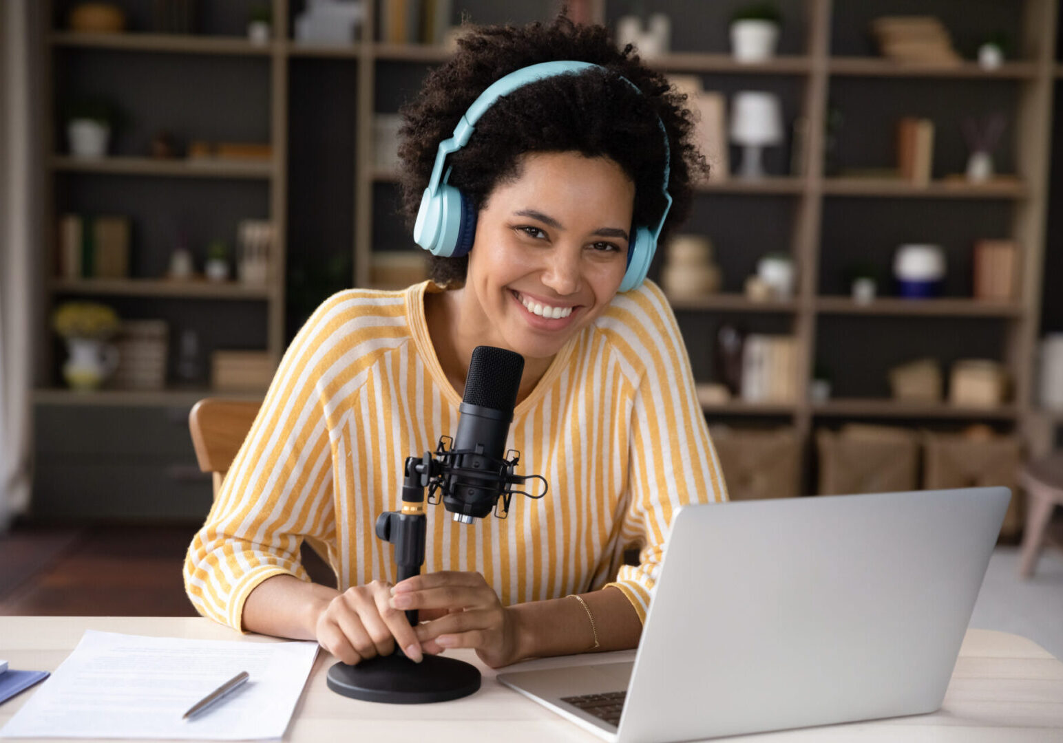 Woman podcasting with microphone and laptop.