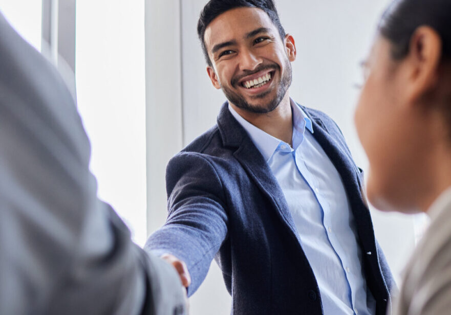 Man smiling while shaking hands in office.