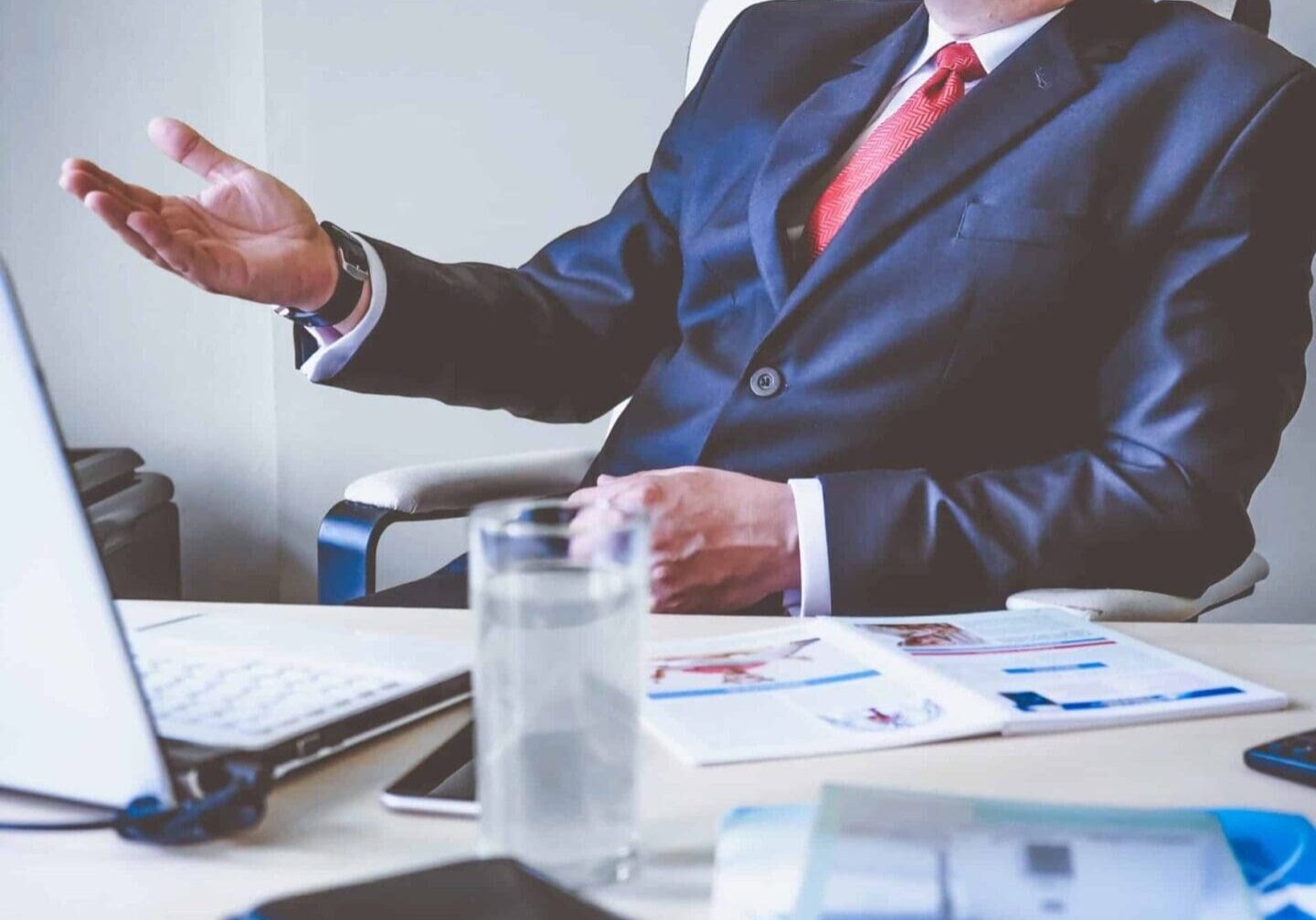 Man in suit gesturing during office meeting.
